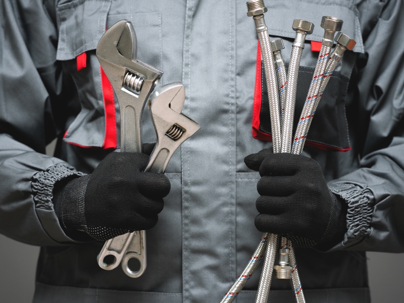 Hydraulik trzymający klucze nastawne i węże elastyczne do instalacji wodnej